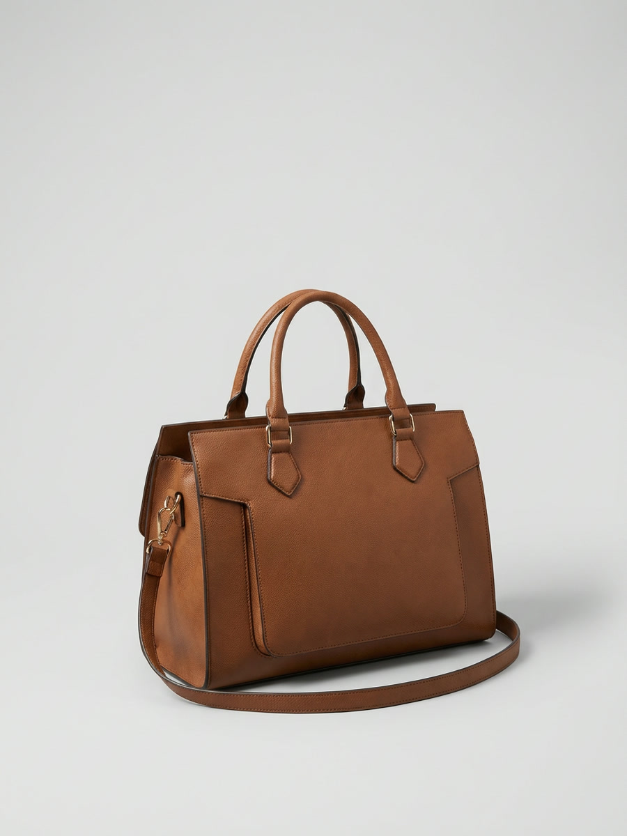 A tan leather holdall on grey seamless